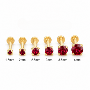 A collection of gold-colored metal piercings with red gemstones, each piercing having a different size indicated by the numbers 1.5mm, 2mm, 2.5mm, 3mm, 3.5mm, and 4mm.