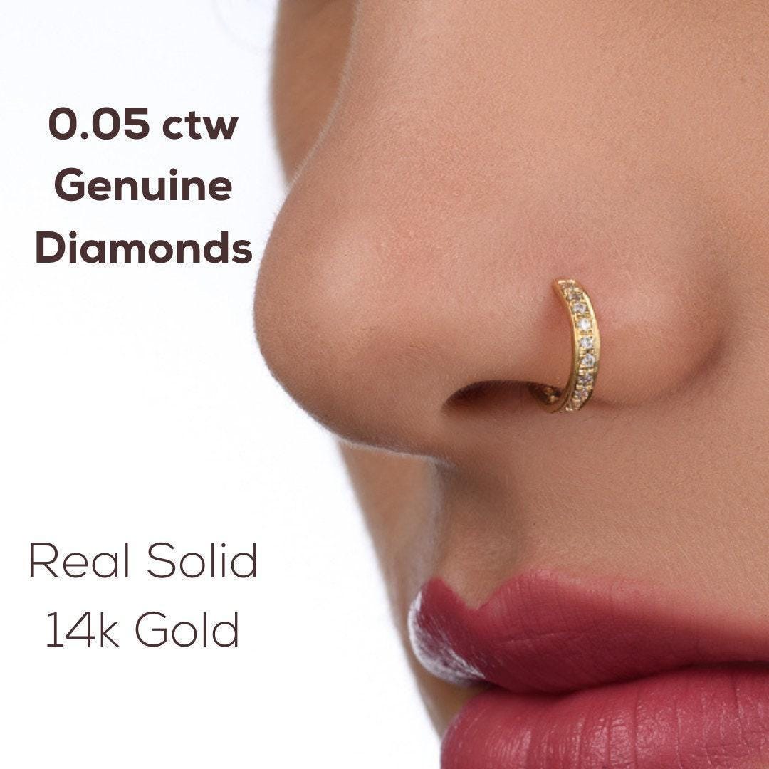 a close-up of a person's nose and lips wearing a gold nose ring with a diamond accent.