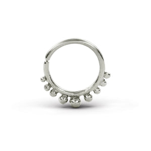 A silver-colored metal ring with a unique design, featuring a central loop and a row of small, round beads or stones protruding from the surface.