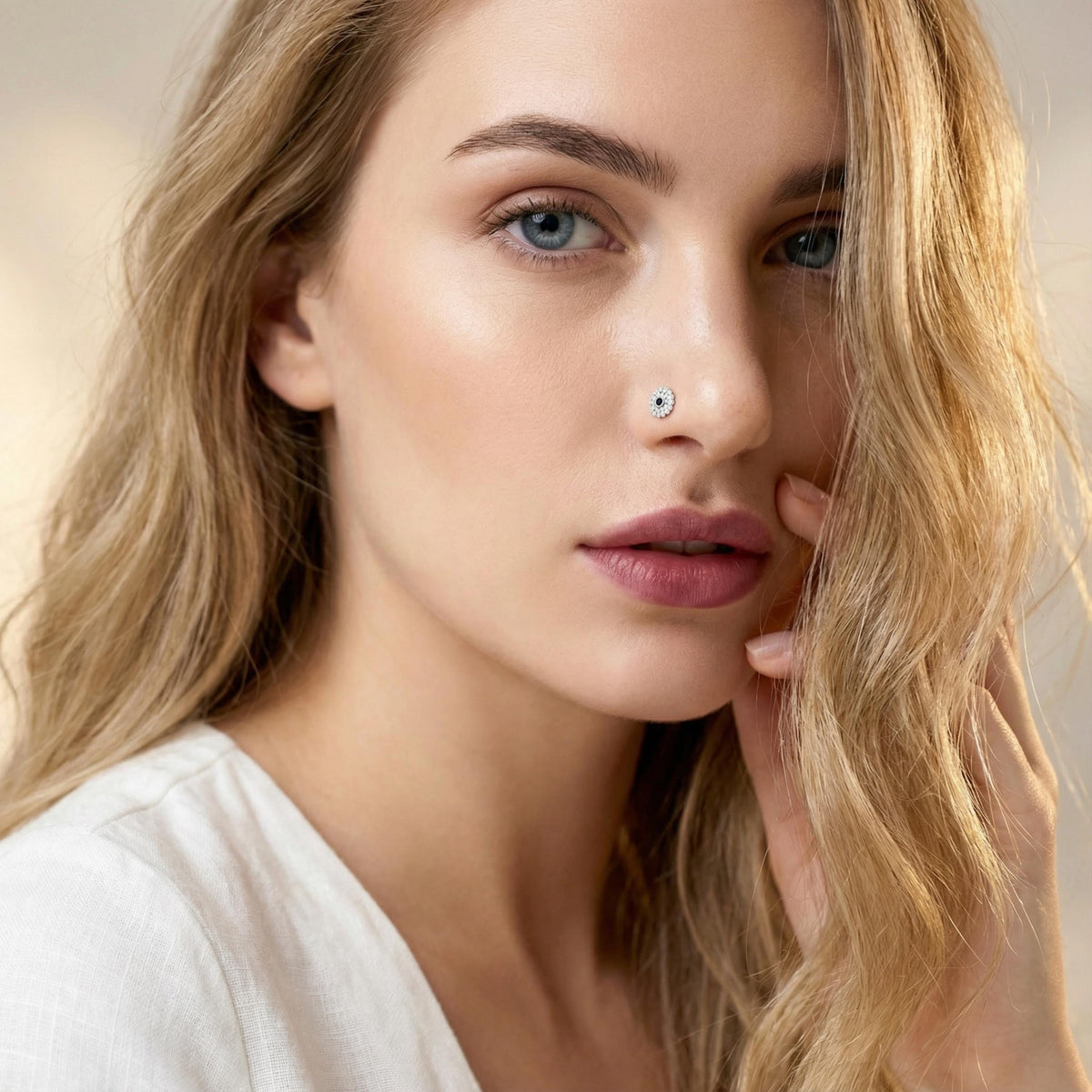 A close-up portrait of a woman with blonde hair, wearing a white top, and looking directly at the camera with a thoughtful expression.