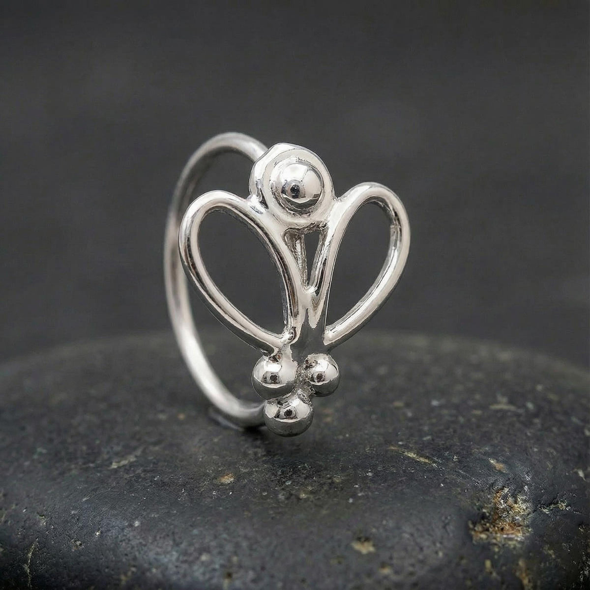 Gold Nose Jewelry: A white gold ring with a unique, intricate design sits on a black surface.