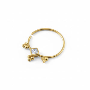 A gold-colored nose ring with a diamond-like gemstone set in the center.