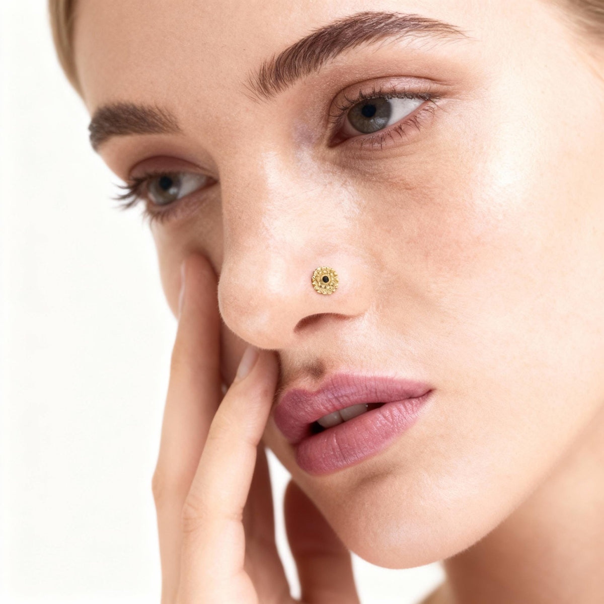 A close-up of a woman's face, focusing on her nose and hand.