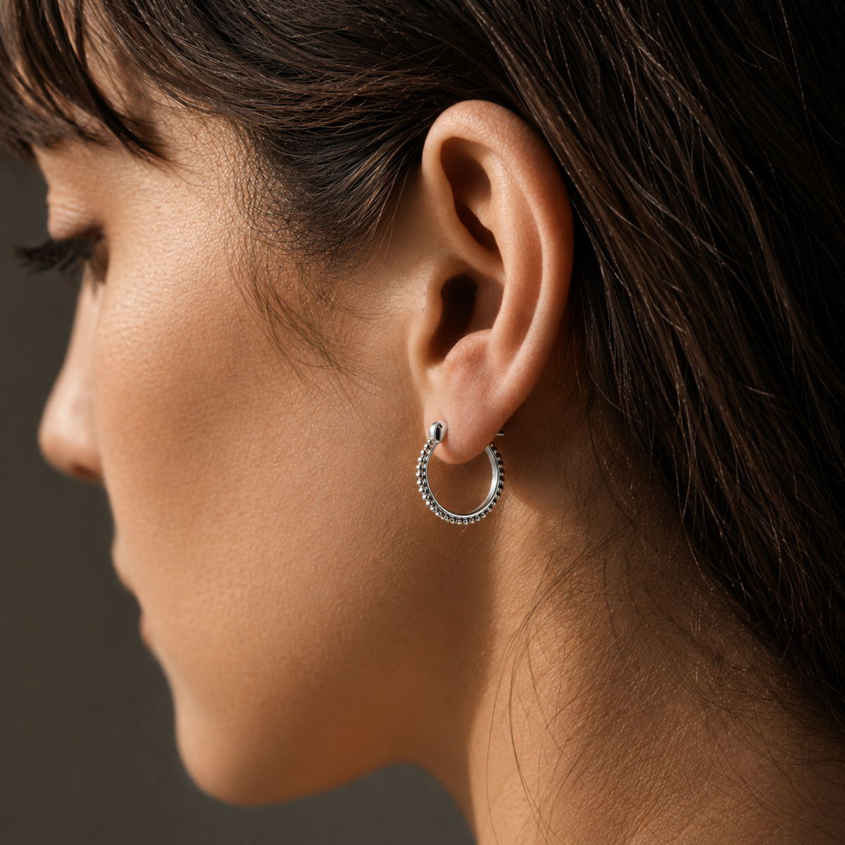 A close-up of a woman's face, focusing on her earrings and hair.