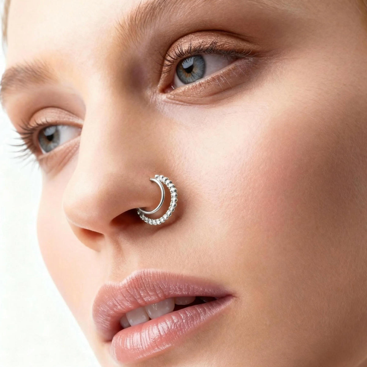 A close-up of a woman's face, focusing on her nose and lips. She has a nose ring and is looking off to the side.