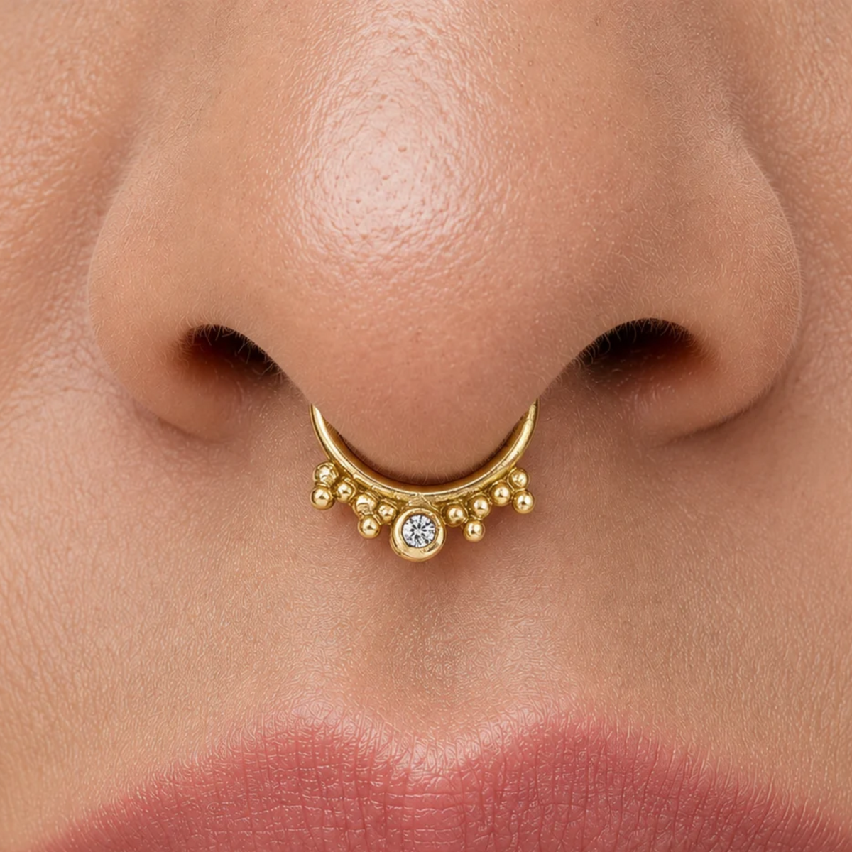 A close-up of a person's nose and lips, with a gold nose ring adorned with small diamonds.