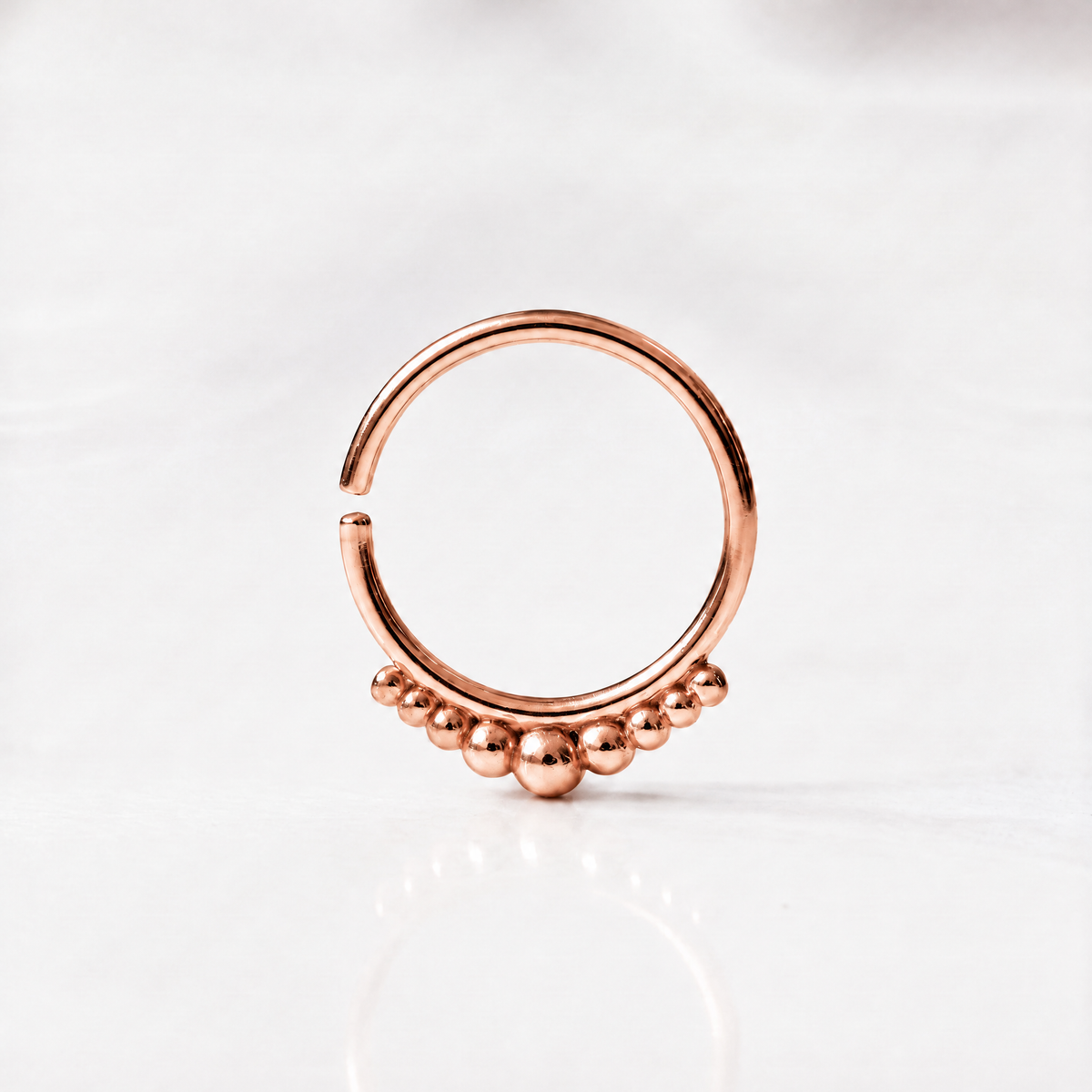 A copper-colored ring with a row of small balls or stones on the surface.