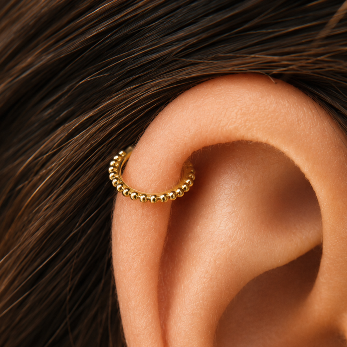 A gold-colored earring with a small ball-like design is visible in the image.
