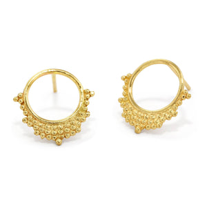 a pair of gold earrings with a circular design featuring small, round, bumpy elements.