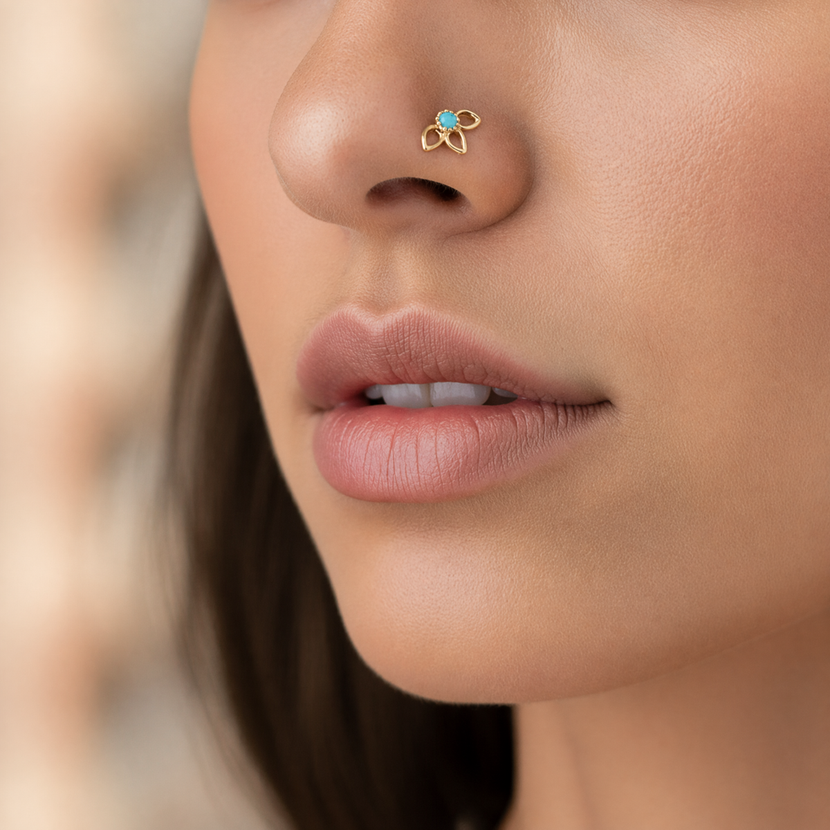 A close-up of a woman's face, focusing on her nose and lips. She is wearing a gold nose ring with a blue gemstone.