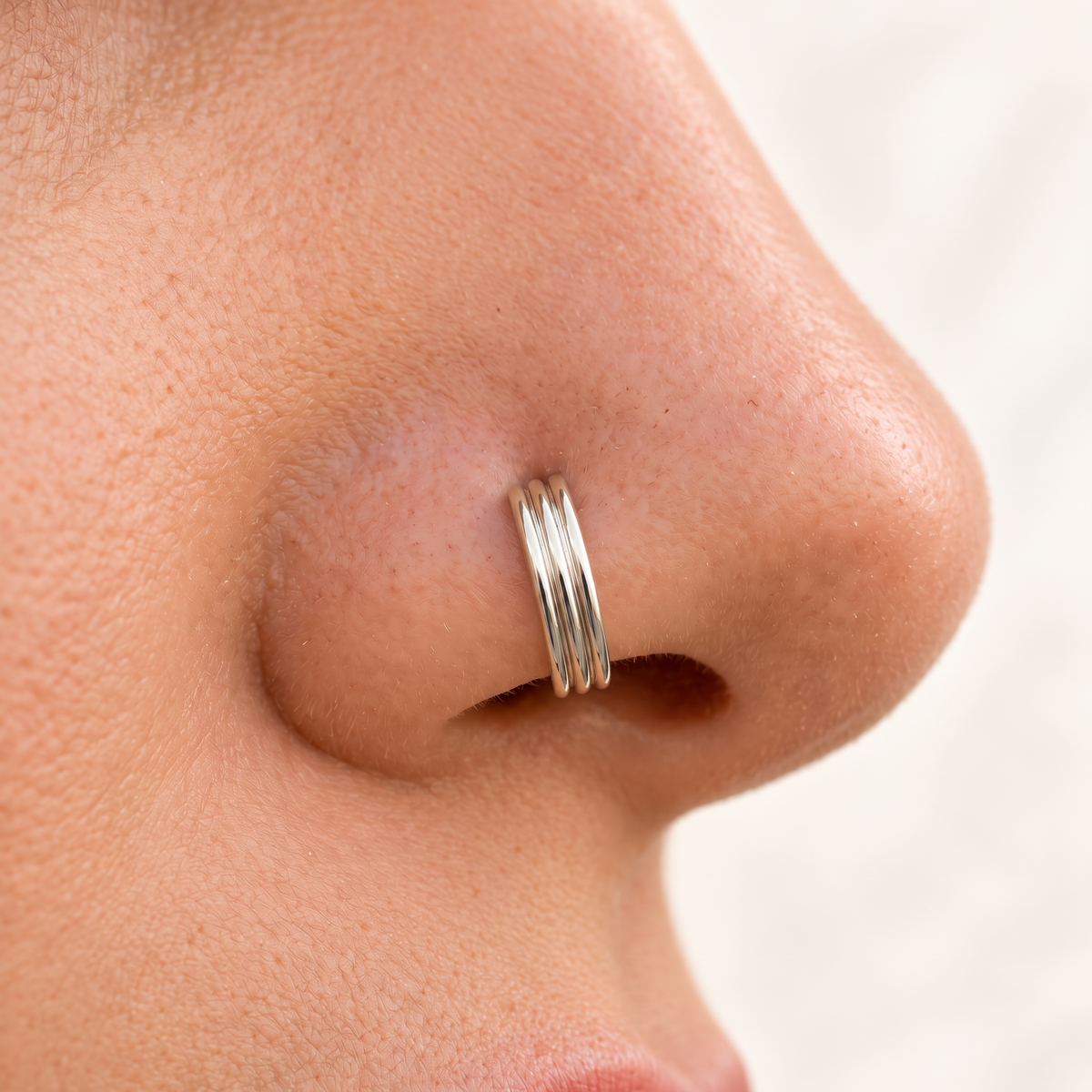 A close-up of a person's nose with a silver nose ring.