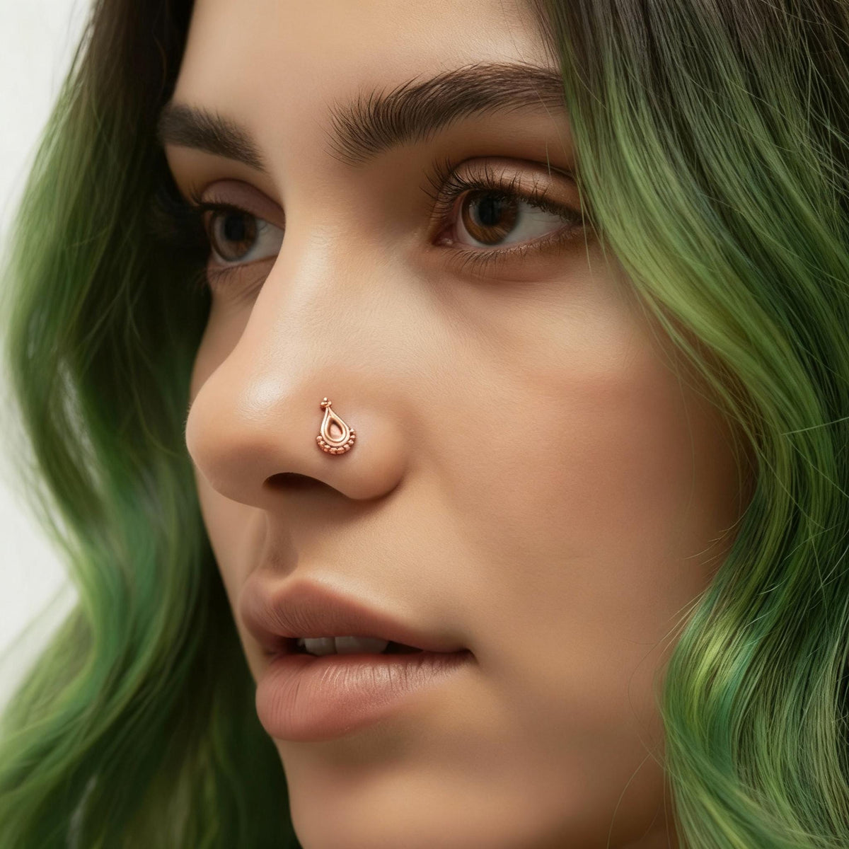 A close-up of a woman's face with green hair, wearing a nose ring.