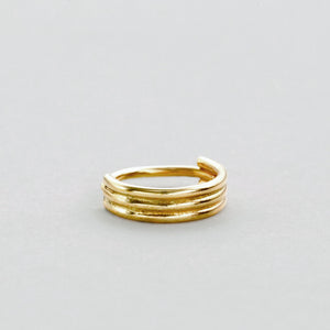 A gold ring with three concentric bands is shown against a light gray background.