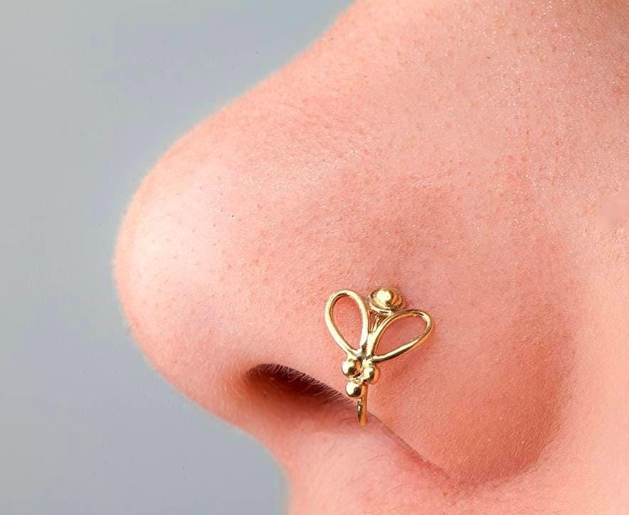 Butterfly Nose Ring: A close-up of a person's nose with a gold-colored nose ring featuring a butterfly design.
