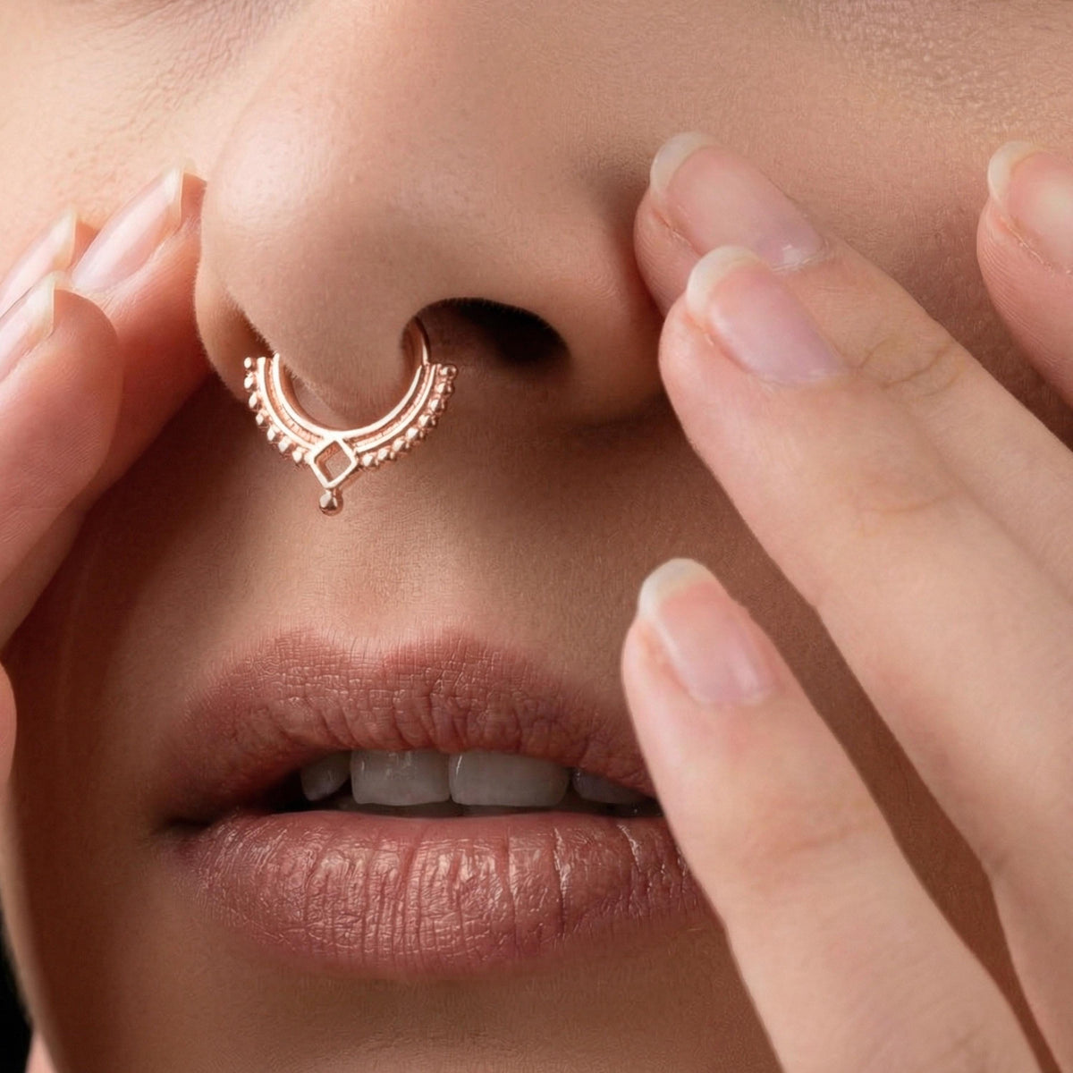 A close-up of a person's face, focusing on their nose and lips, with a nose ring and fingers partially covering the mouth.