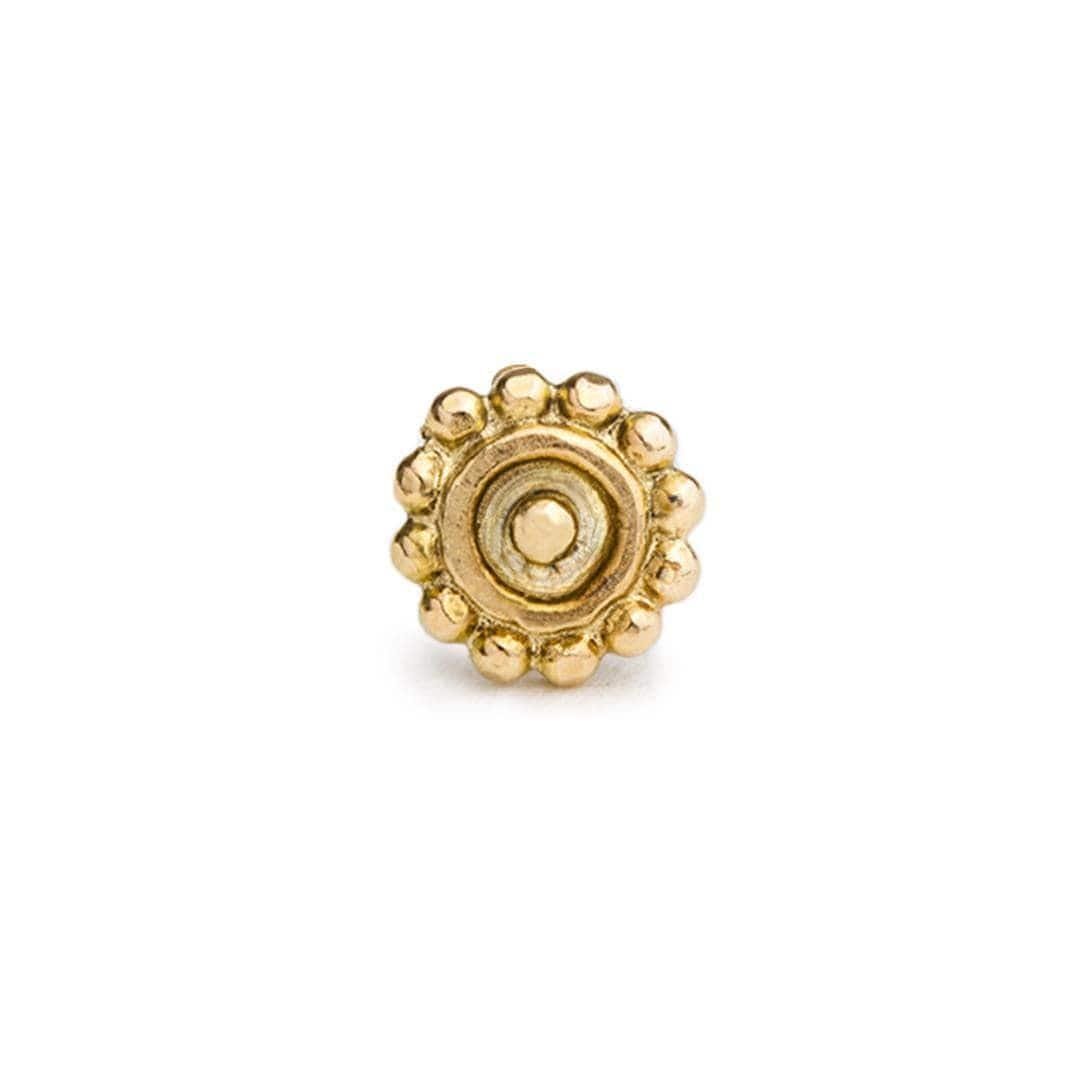A single, ornate gold-colored object with a central circular design surrounded by a ring of smaller, round, shiny balls.