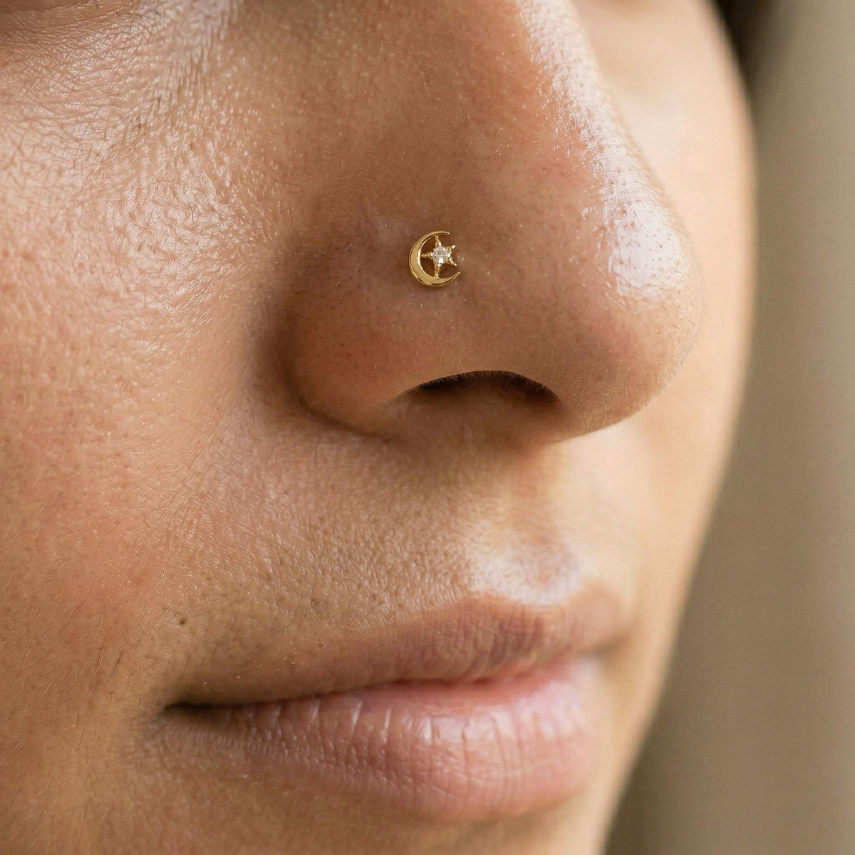 A close-up of a person's nose with a small gold-colored nose stud or piercing.