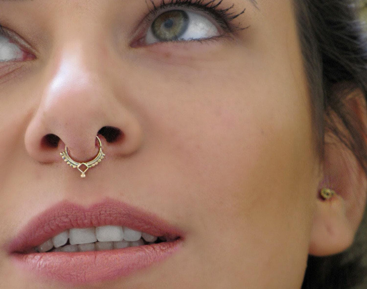 Tribal 14k Solid Gold Septum Ring: A close-up of a woman's face, focusing on her nose and lips, with a piercing in her nose.