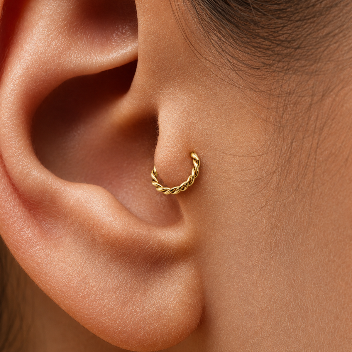 A close-up view of a person's ear with a gold-colored metal ring or piercing in the earlobe.