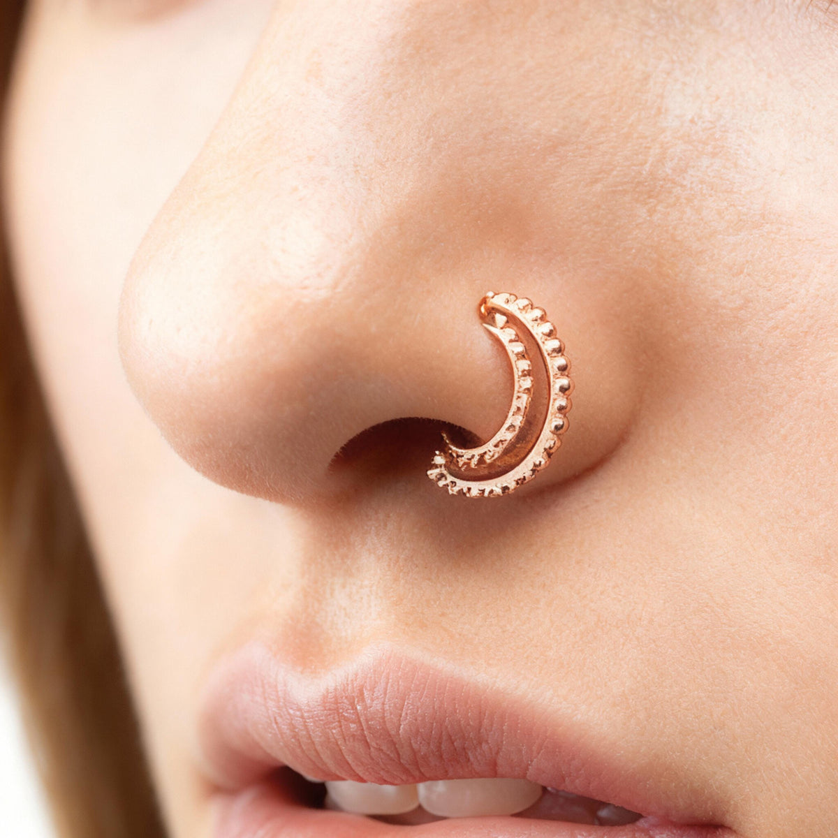 Indian Nose Hoop: A close-up of a person's nose with a decorative nose ring featuring a crescent moon design.