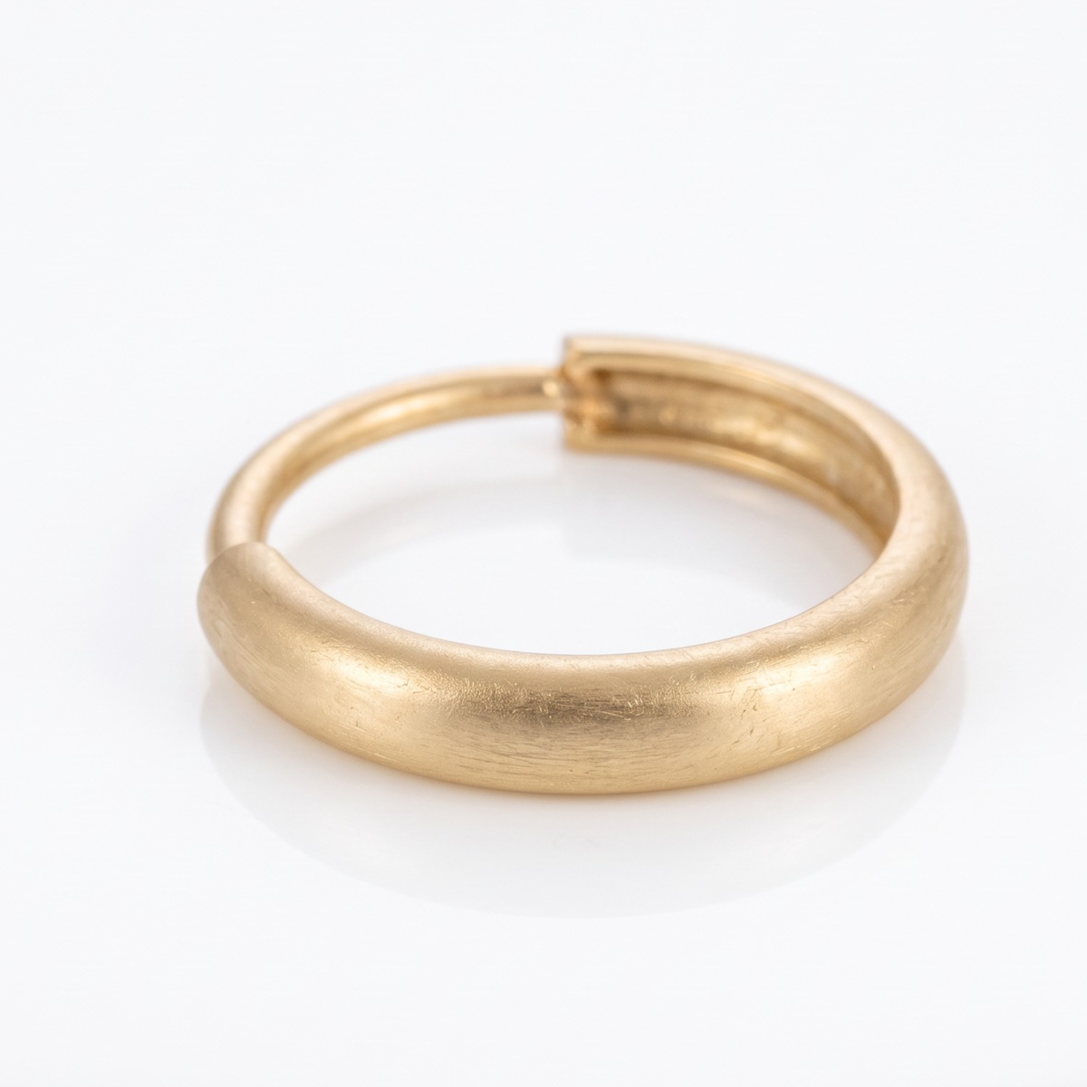 A gold-colored, round, metallic ring is shown against a white background.