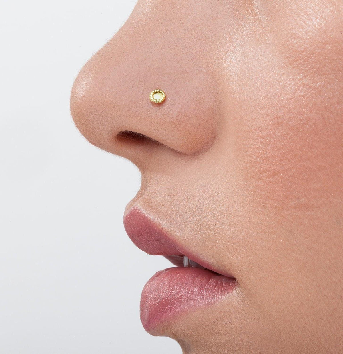 Minimalist Gold Nose Stud: A close-up of a person's face, focusing on their nose and mouth area.