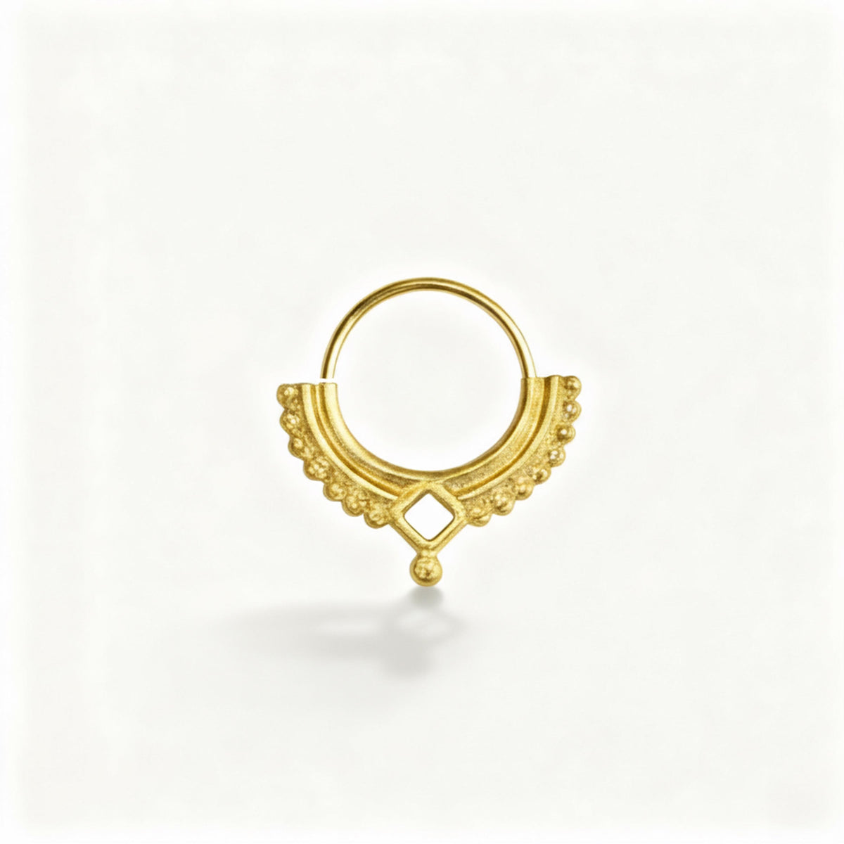 A gold-colored metal ring with a decorative design, featuring a small gemstone or bead at the center.