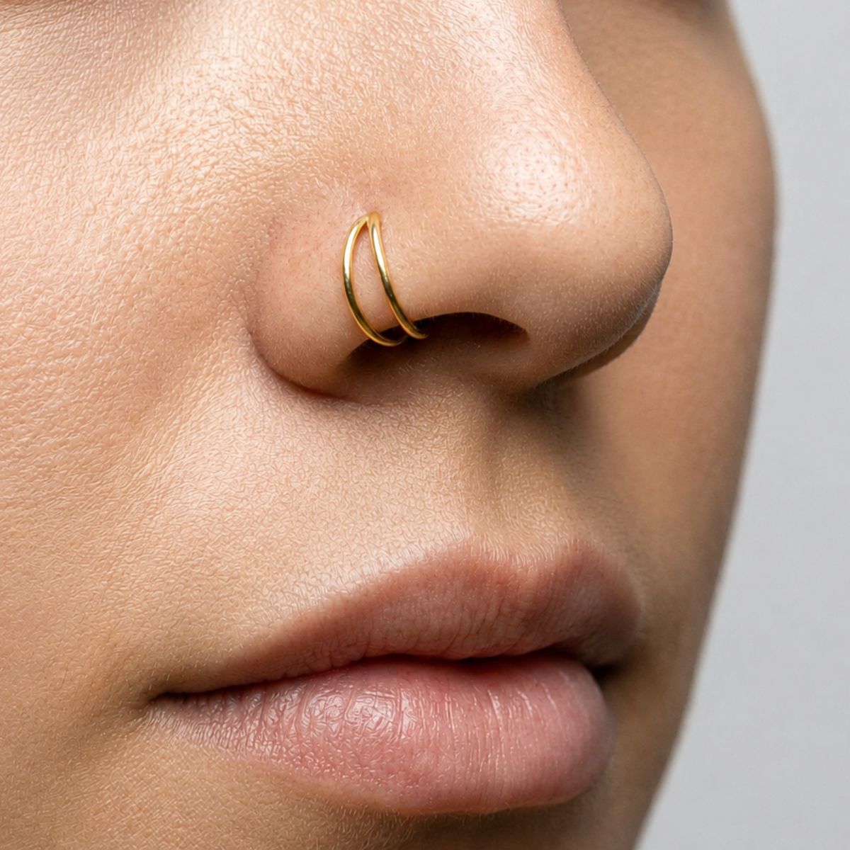 A close-up of a person's nose and mouth, with a gold-colored nose ring visible.
