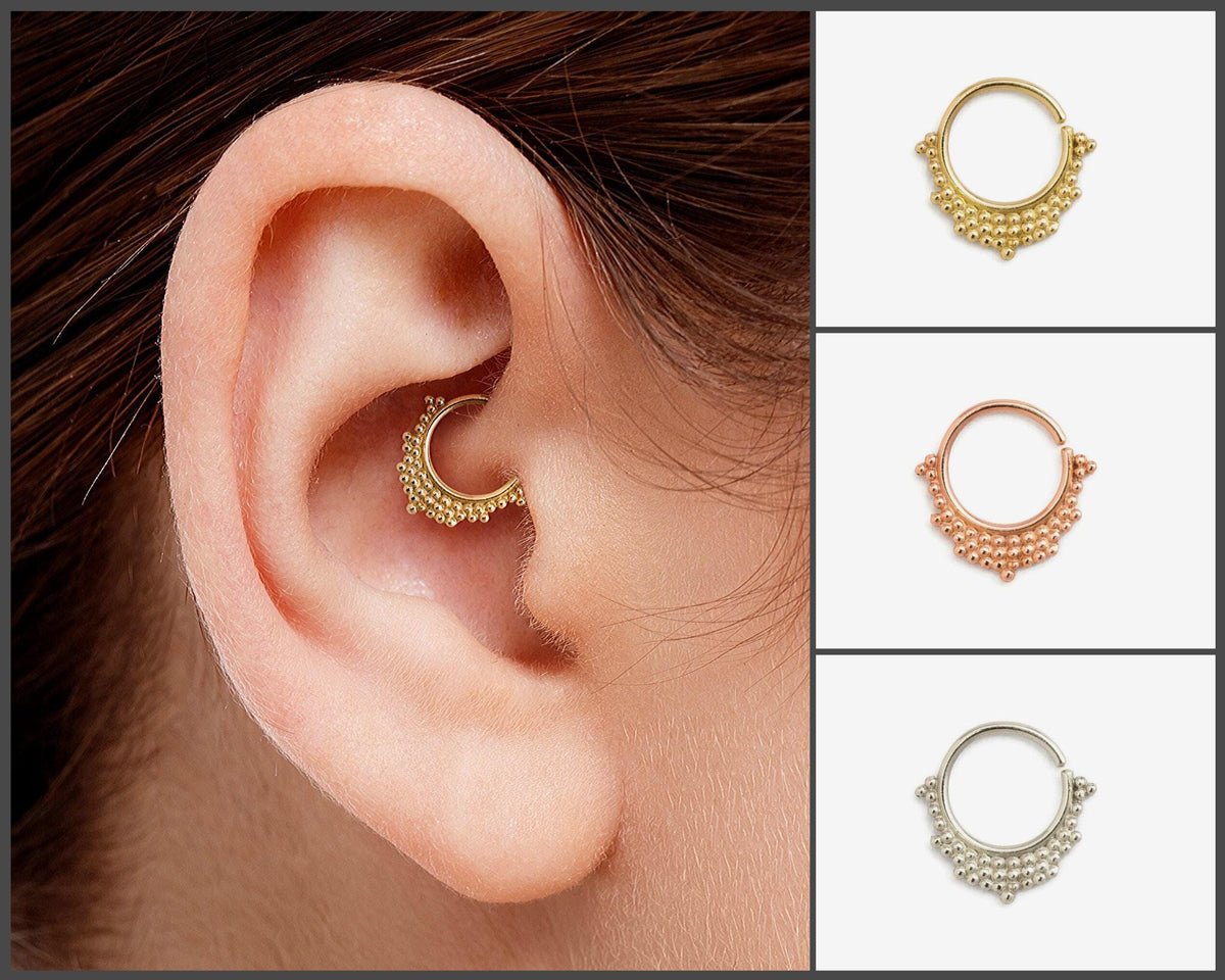 A close-up of a person's ear with a gold-colored piercing ring, and three smaller images of similar rings in different colors - gold, silver, and white.