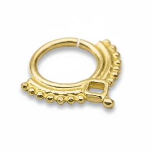 A gold-colored metal ring with a decorative design, featuring a central square-shaped element surrounded by a row of small, round beads or dots.