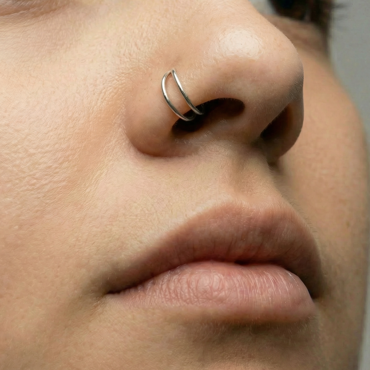 A close-up of a person's nose and mouth, with a silver nose ring visible.