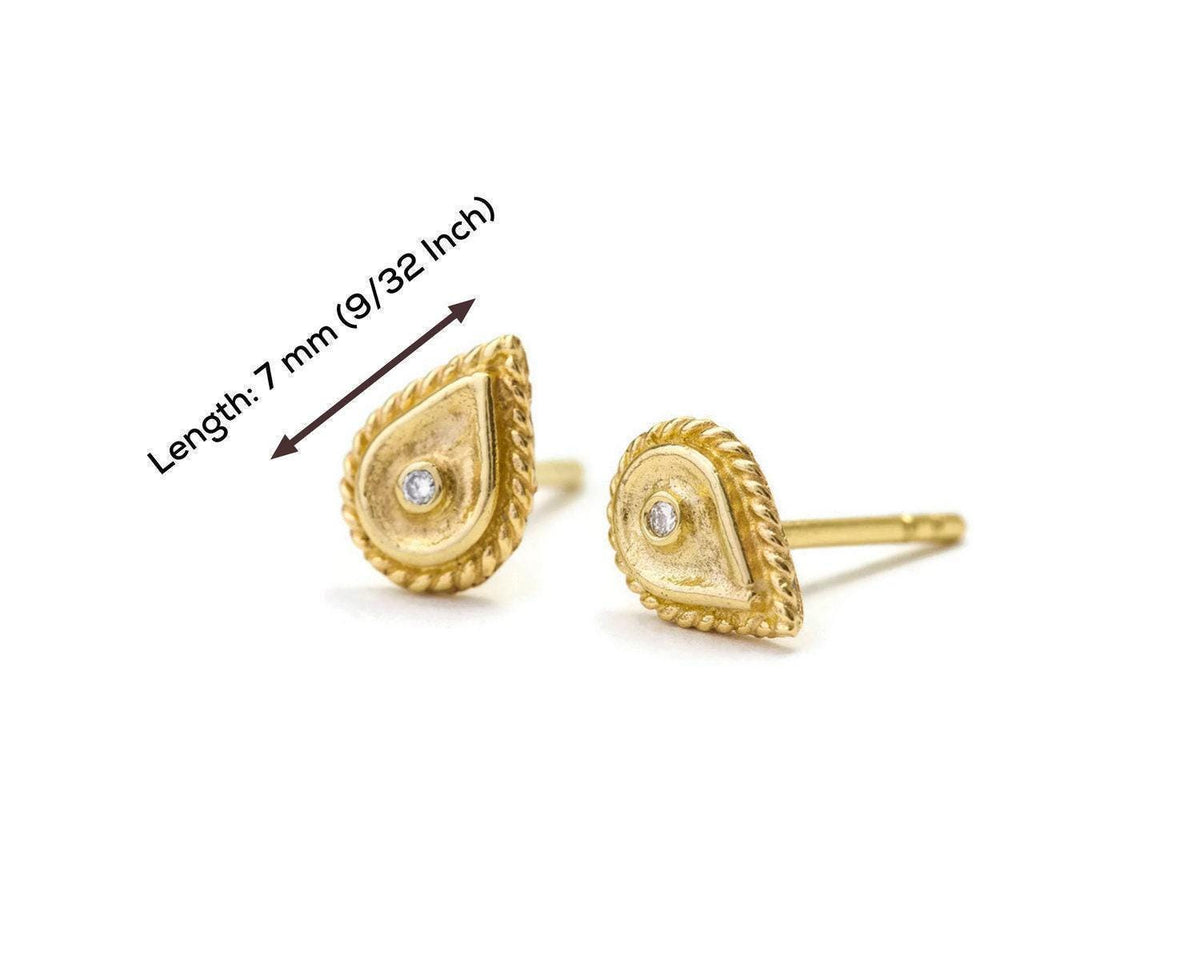 two gold earrings with a diamond in the center, with a ruler indicating their length.