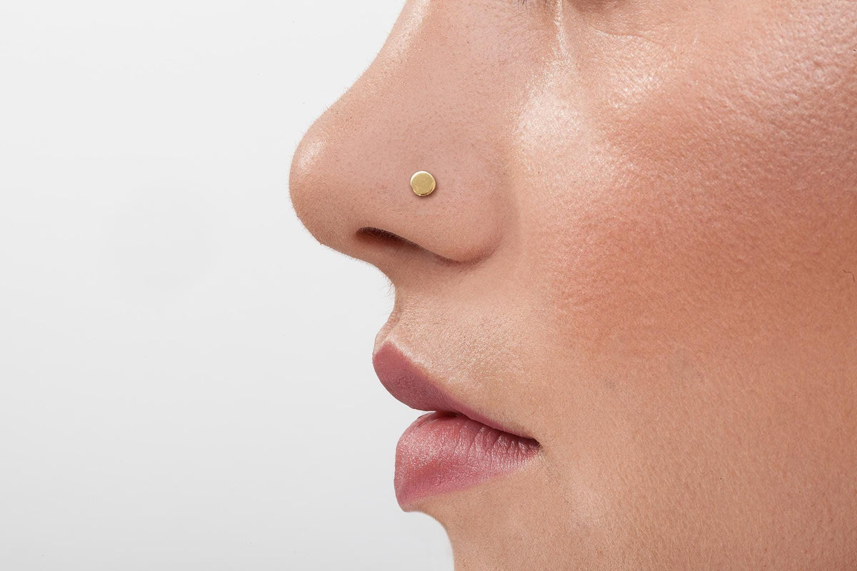 Solid Gold Nose Stud: A close-up of a person's face, focusing on their nose and mouth area.