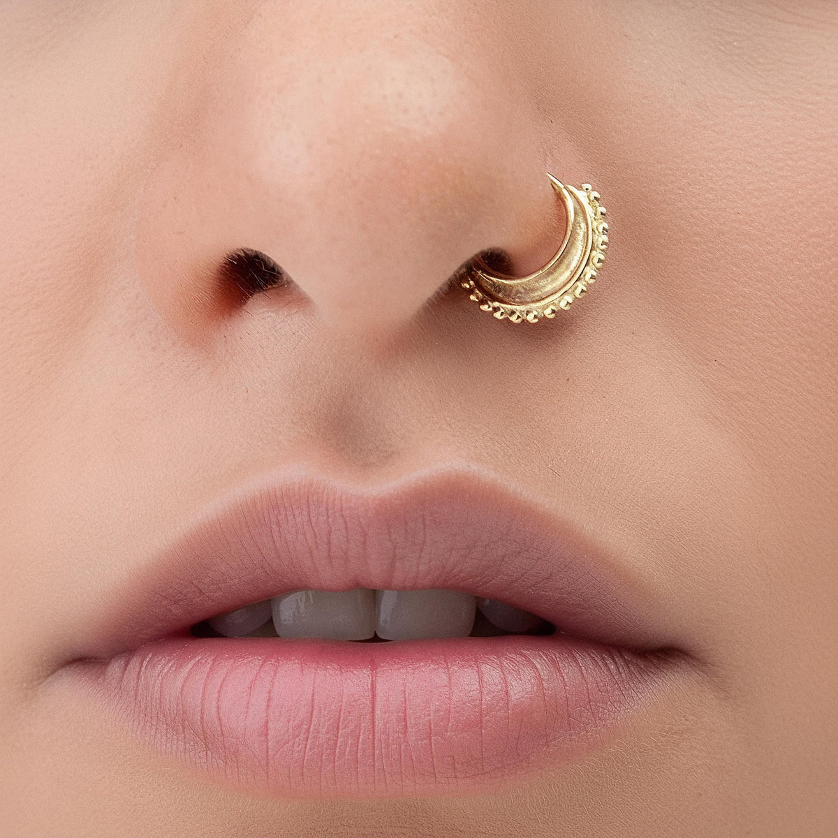 Solid 14K Gold Nose Ring: A close-up of a person's face, focusing on their lips and nose.