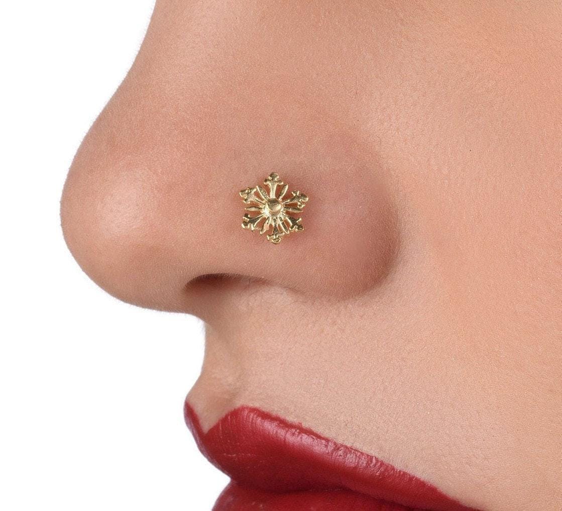 Large Gold Nose Ring: A close-up of a person's face, focusing on their nose and lips. The nose is adorned with a small, ornate gold nose ring.
