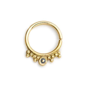 A gold-colored metal ring with a small blue gemstone in the center.