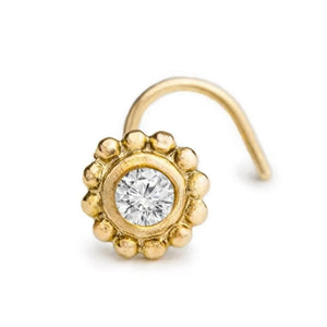 A gold-colored nose ring with a large, clear gemstone set in the center.