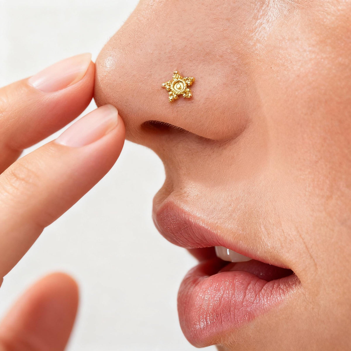 A close-up of a person's face, focusing on their nose and lips, with a small gold-colored star-shaped nose stud.