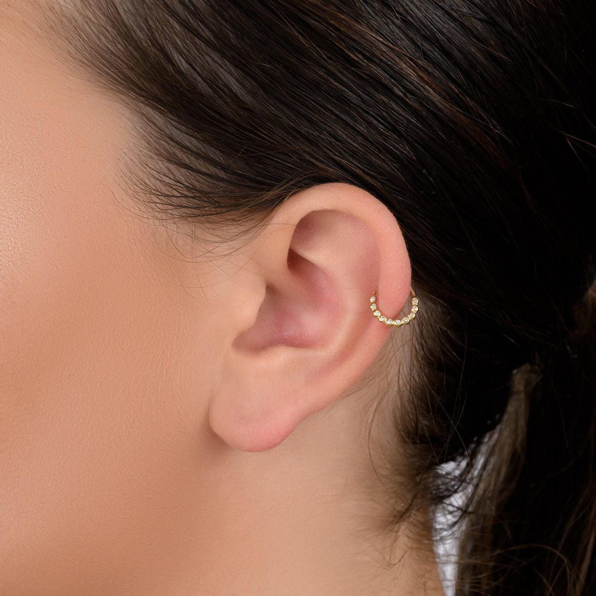 A close-up of a person's ear with a gold hoop earring.