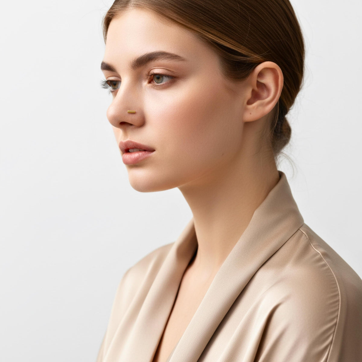 A woman with brown hair wearing a beige jacket is shown in profile against a plain white background.