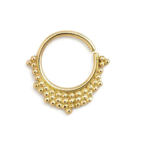 A gold-colored metal ring with a decorative design featuring small balls or beads around the edges.