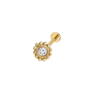 A gold-colored nose ring with a large, clear gemstone in the center.