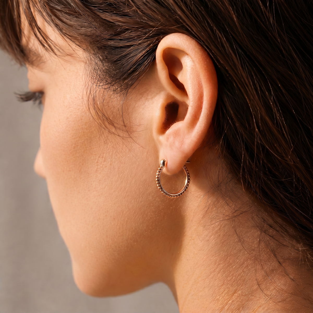 A close-up view of a woman's face, focusing on her earrings and hair.