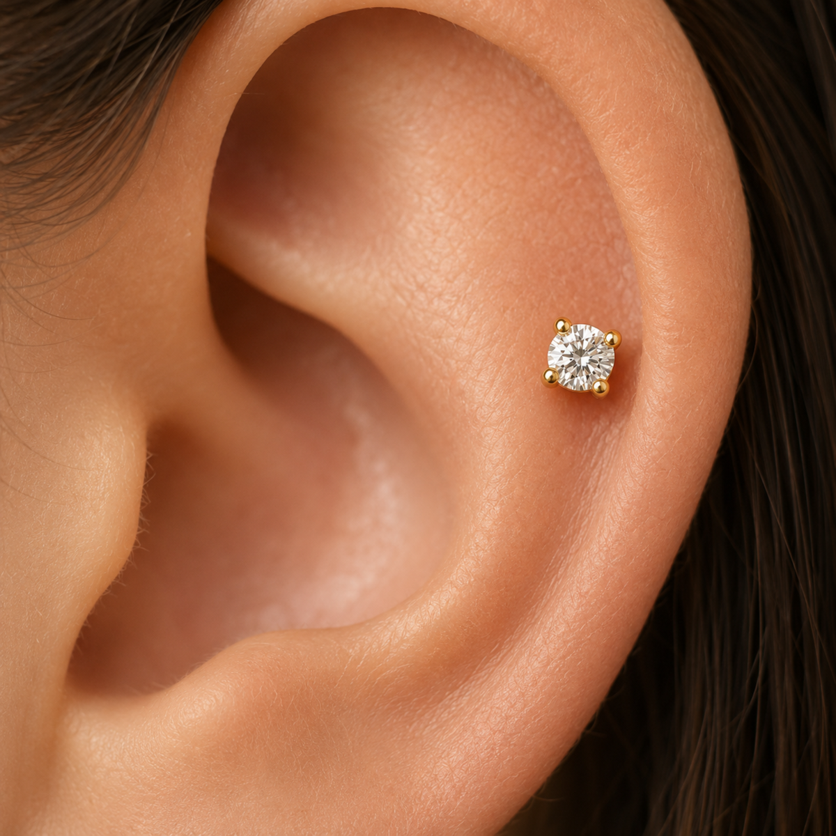 A close-up of a person's ear with a small diamond earring in the earlobe.