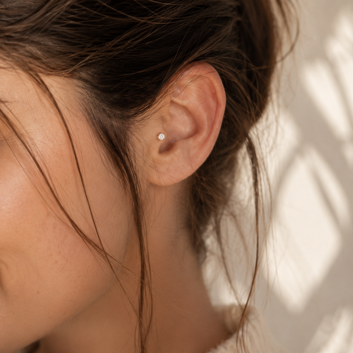 A close-up of a person's ear with a small diamond earring in it.