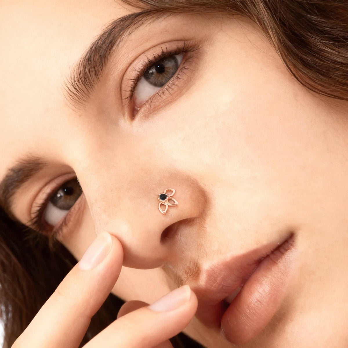 A close-up of a woman's face, focusing on her nose and fingers.