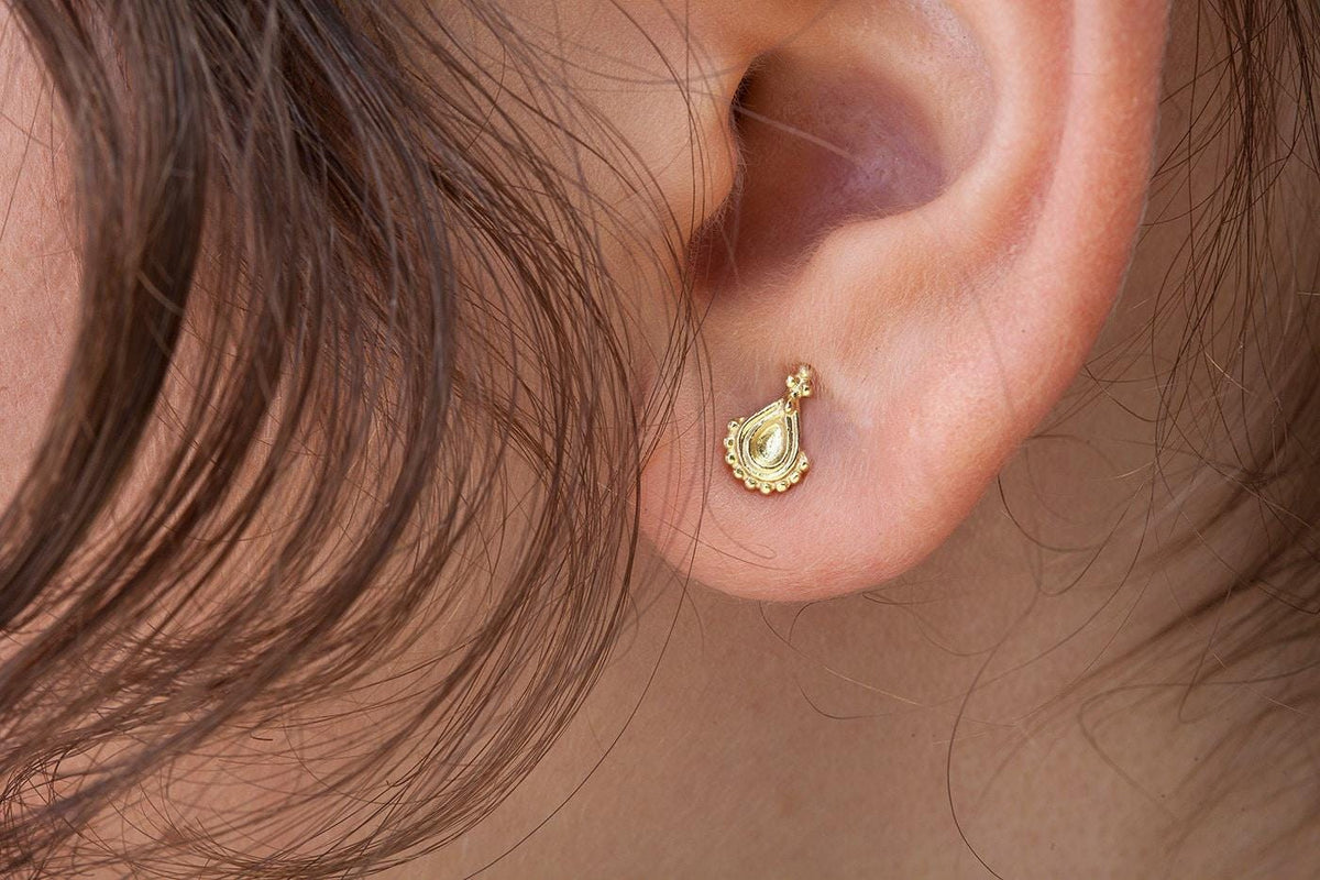 A close-up view of a person's ear with a small gold earring in the earlobe.