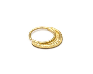 A gold-colored metal ring with a curved design, resting on a white background.