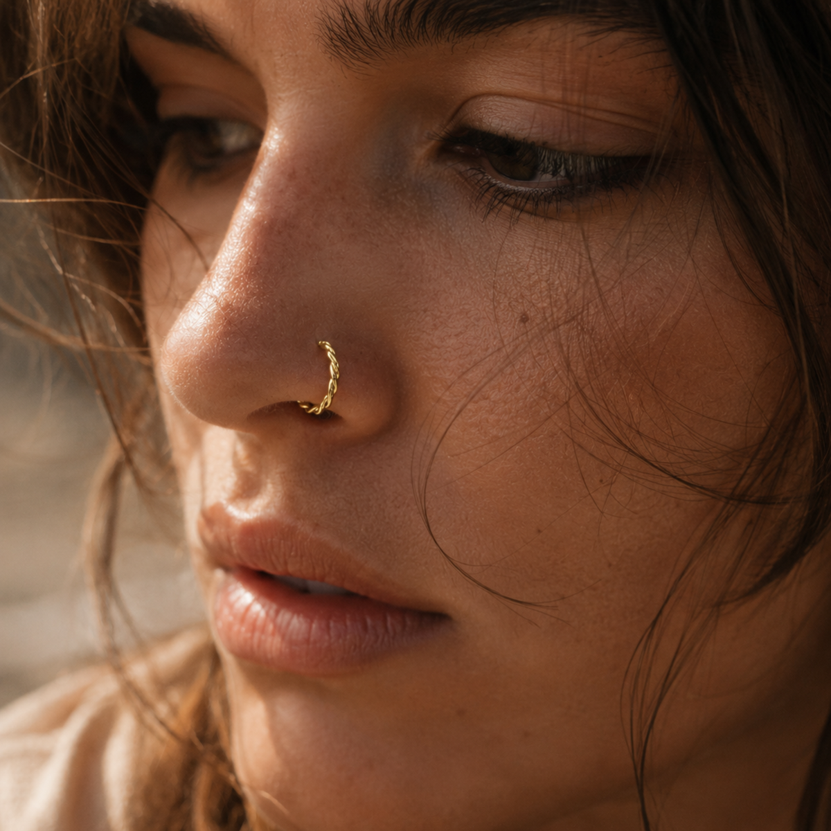 A close-up of a woman's face, focusing on her nose and lips, with a gold nose ring visible.