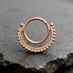 Nostril Hoop: A copper-colored metal ring with a twisted, braided design sits on a dark surface.